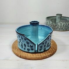 two blue dishes sitting on top of a cork coaster next to each other and one has a candle holder in the middle