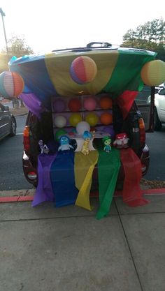 a cart with balloons and other decorations on the back parked in front of a parking lot