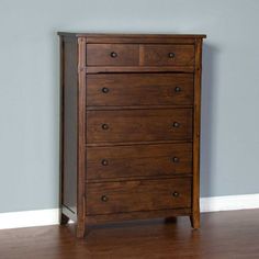 a wooden dresser sitting on top of a hard wood floor next to a gray wall