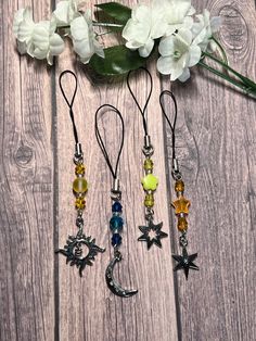 four different necklaces with stars and moon charms hanging from them on a wooden surface