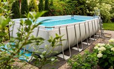 an above ground pool surrounded by flowers and greenery