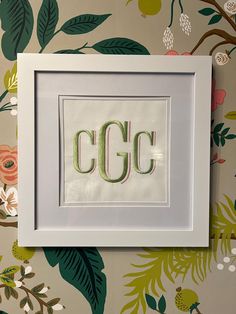 there is a picture frame with the word ccc in it and flowers on the wall