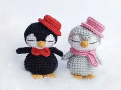 two small crocheted penguins are standing next to each other on snow covered ground