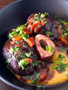 a black bowl filled with food on top of a wooden table