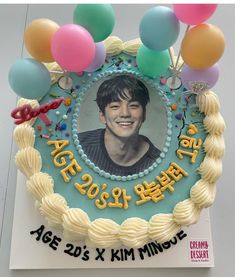 a birthday cake decorated with balloons and an image of a young man's face