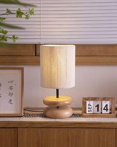 a lamp sitting on top of a wooden table next to a clock and calendars