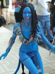 a woman dressed in blue with dreadlocks and makeup