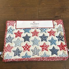 a red, white and blue quilted placemat with stars on it sitting on a wooden floor