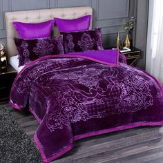 a bed with purple comforters and pillows