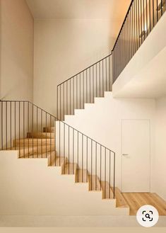 there is a staircase in the middle of this room with wood floors and white walls