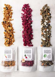 four bags of granola are lined up on a white surface, each with different flavors