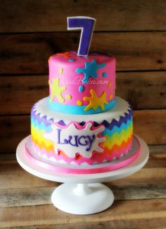 a birthday cake with the number one on it is decorated in bright colors and sprinkles