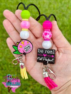 a hand holding three different key chains in it's left hand, with the words be real on them