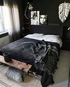 a bedroom with black walls and white bedding, artwork on the wall above it