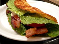 a sandwich with bacon, lettuce and tomato on it sitting on a white plate