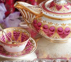 a pink and gold tea set sitting on top of a table