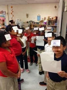 several children are standing in a room with papers taped to their faces