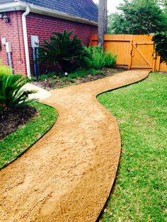 a path in the yard leading to a house with a wooden fence and brick building behind it