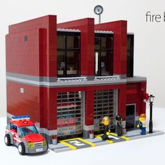 a lego fire station is shown with two firefighters standing in front of the building and one on the sidewalk