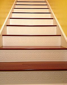 a cat sitting on top of a set of stairs next to a wall with yellow walls