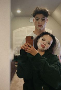 a man taking a selfie in front of a mirror with a woman wearing a face mask