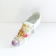 a pair of white shoes with flowers and pearls on the bottom, sitting against a white background