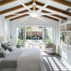 a bedroom with white walls and wooden ceiling beams, large bed in the foreground