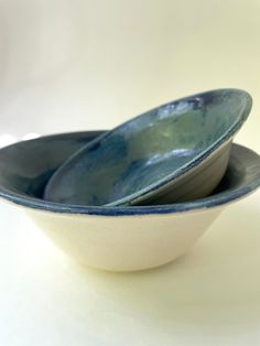 two blue and white bowls sitting side by side on a white tableclothed surface