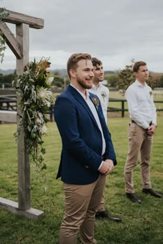 three men standing in front of a wooden cross