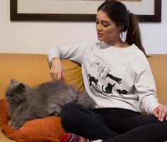 a woman sitting on a couch petting a cat