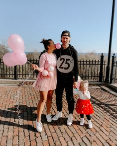 a man, woman and child posing for a photo with balloons in front of them