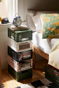 a stack of books sitting on top of a wooden table next to a bed in a bedroom