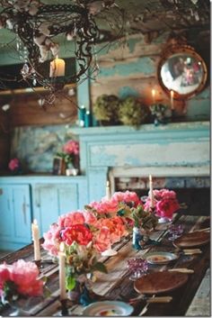 a dining room table with flowers and candles on it, in front of a fireplace