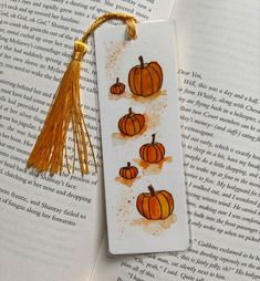 a bookmark with three pumpkins on it sitting on top of an open book