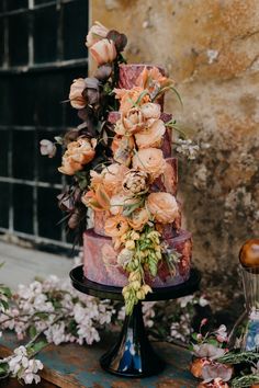 a multi - tiered cake with flowers and greenery sits on top of a table