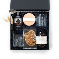 an assortment of liquors and condiments in a black gift box on a white background