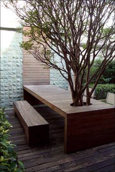 a wooden table and bench sitting on top of a wooden deck next to a tree