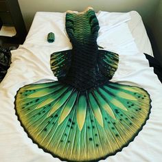 a green and yellow fan sitting on top of a white bed next to a pillow