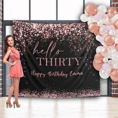 a woman standing in front of a birthday banner