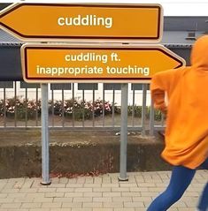 a person in an orange hoodie is walking by a sign