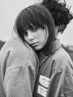 a woman with her arm around the back of a man's shoulder, in black and white