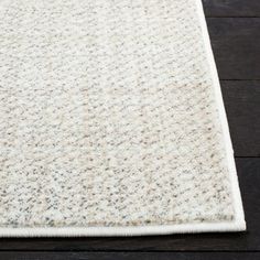 a white area rug on top of a wooden floor next to a remote control device