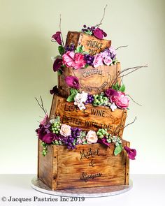 a three tiered cake with flowers and wine crates on the top is made out of wood