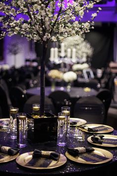 the table is set with black and white plates, silverware, and a tree