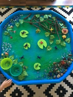 a child's hands holding a blue tray filled with water and plants