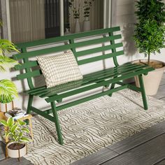 a green bench sitting on top of a wooden floor next to a potted plant