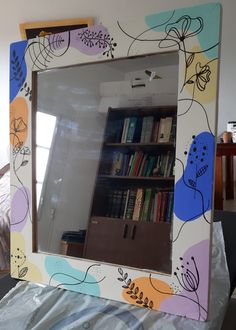 a mirror that is sitting on top of a bed in front of a book shelf