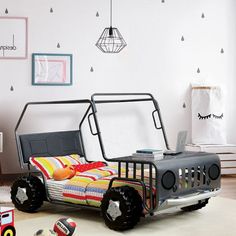 a child's bedroom with a toy car bed and toys on the floor in front of it