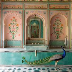 a peacock is standing in front of a wall with flowers and paintings on it's walls