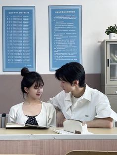 two people sitting at a table with an open book